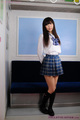 Student in uniform wearing plaid skirt long hair hands clasped behind her back