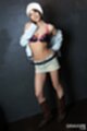 Luna standing against dark grey wall hand on hip wearing black lacy bra and short skirt in brown boots