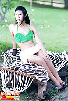 Seated on white netting wearing green top in short skirt